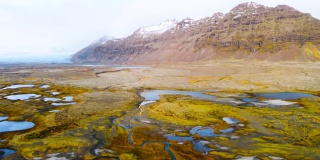 神奇的空中飞行在冰岛上空，从鸟瞰，这里是一片有着黄色苔藓和蓝绿色湖泊的火山景观。美丽而原始的自然