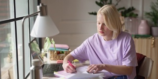 年轻女性在家工作或学习时做笔记