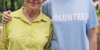 年轻的志愿者拥抱微笑的老女人，老人关怀，陪伴