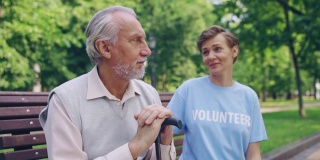 善良的志愿者支持一位悲伤的老人，坐在公园的长椅上，帮助他