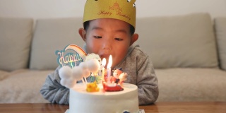 小男孩在吹生日蛋糕上的蜡烛