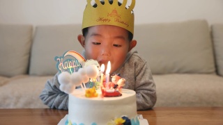 小男孩在吹生日蛋糕上的蜡烛视频素材模板下载