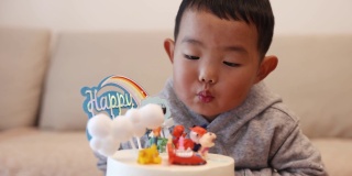 小男孩在吹生日蛋糕上的蜡烛