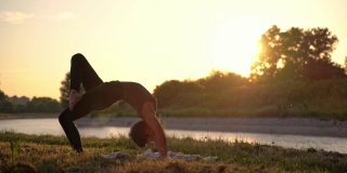 日落时分在河边做瑜伽的女人