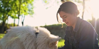 一名女子在公园里给瑞士牧羊犬喂食