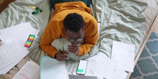 男学生在家学习时使用智能手机