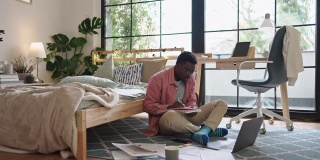 一个年轻的学生坐在地板上，周围是书、纸和笔记本电脑