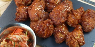 韩式炸鸡配辣酱传统的韩式食物，炸鸡配米饭和泡菜放在木桌上。