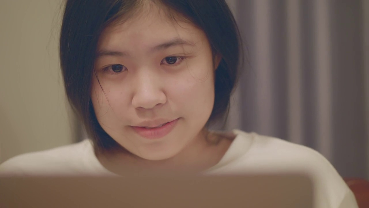 亚洲妇女看着笔记本电脑，笑得很开心