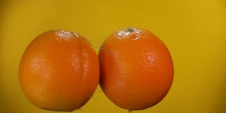 两个多汁的橘子在飞，互相碰撞着上升的水滴