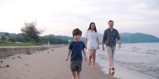 快乐的一家人在周末的沙滩上散步和跑步。