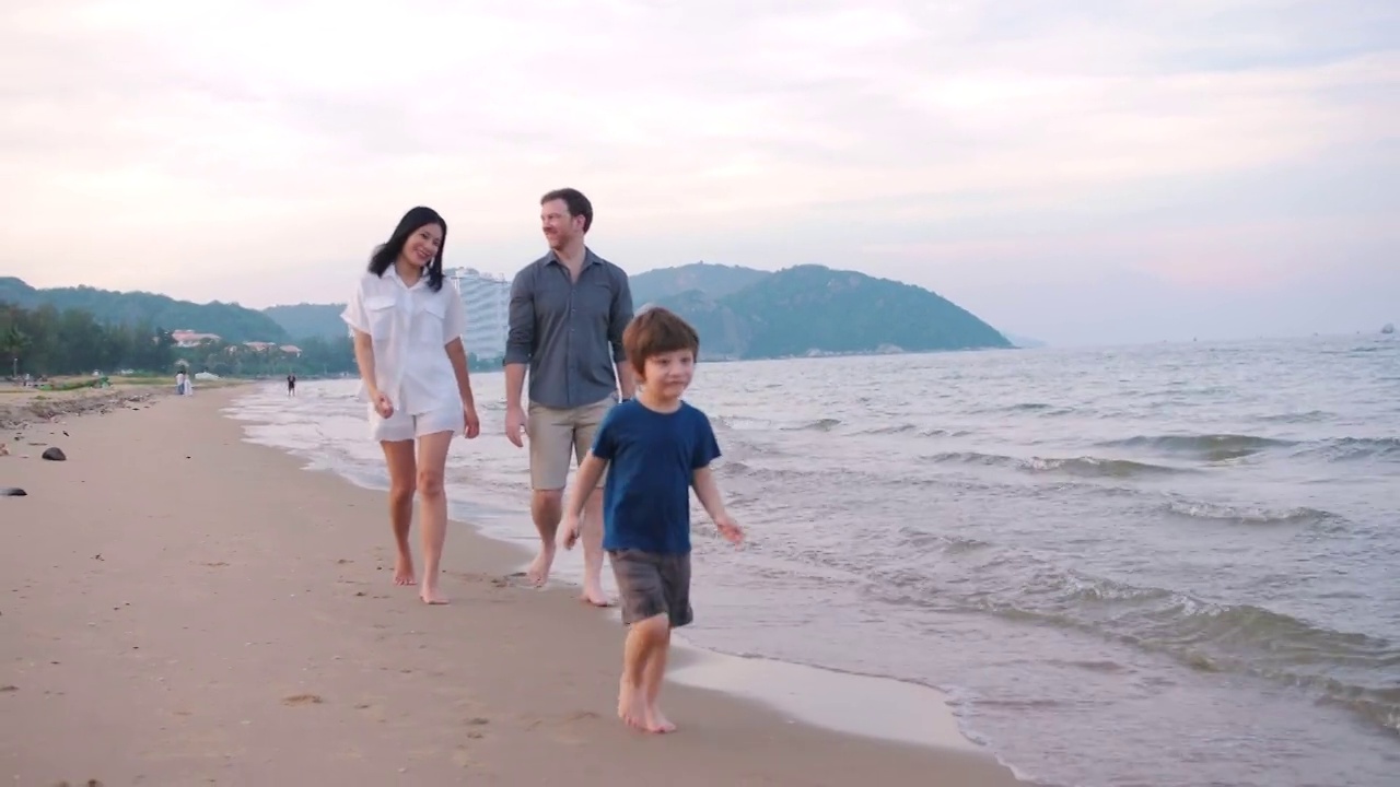 有一半美国血统的家庭在日落海滩漫步。