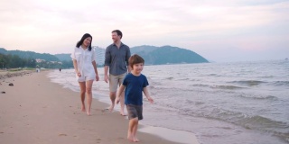 有一半美国血统的家庭在日落海滩漫步。