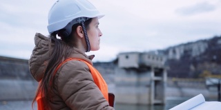 在水电站大坝工作的女工程师。以生态为导向。可再生能源系统。