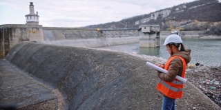 在水电站大坝工作的女工程师。以生态为导向。可再生能源系统。