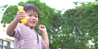 慢镜头:快乐的亚洲小男孩和他的妈妈在家里一起玩肥皂泡
