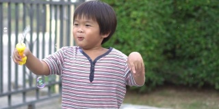 慢镜头:快乐的亚洲小男孩和他的妈妈在家里一起玩肥皂泡