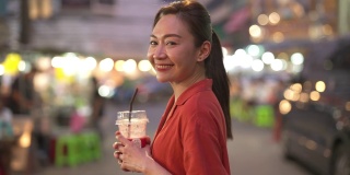 4K亚洲妇女购物和喝果汁，走在街头夜市