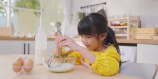 近距离亚洲快乐的年轻女孩在厨房做自制的面包店。可爱的小孩坐在桌子上，感觉快乐，享受在家学习烹饪食物或用手烘焙酵母面团