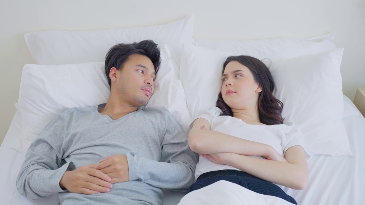 亚洲年轻夫妇躺在床上痛苦的争吵后打架。新婚男女因争吵冲突而心碎，睡在卧室里。家庭problem-separation概念。