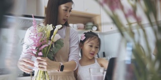 亚洲女性花商与她的女儿谈话，在厨房使用数字平板电脑指导工作