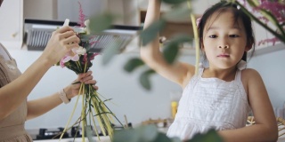 亚洲华人女性花商和女儿插花。每天早上经营小生意的例行公事和家庭团聚的时间