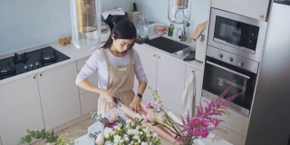 亚洲华人女性花商，小企业主，在厨房为花束剪包装纸，在家里工作，日常运作一个小生意