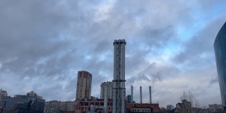 多云阴沉的天空和蒸汽烟从巨大的管道。供热站为邻近的工业设施和住宅提供电力和热量。基辅城市工业景观。
