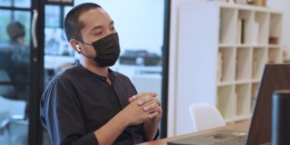亚洲商人戴着口罩在笔记本电脑上工作