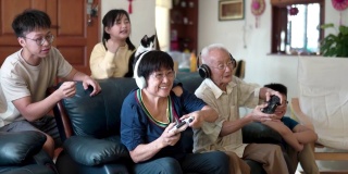 2名亚裔中国祖父母在家里和孙辈玩电子游戏。