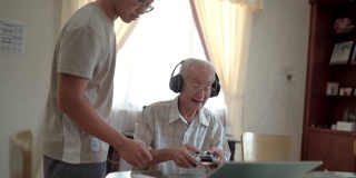 亚洲华人爷爷玩网络游戏在家教孙子。