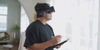 亚洲男子佩戴3D VR眼镜工作，在家享受体验。