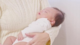 可爱的睡着的新生儿放松在妈妈的手臂安全舒适。微笑亚洲新生儿宝宝休息睡觉香甜的梦。母亲抱着婴儿。新生儿的概念视频素材模板下载