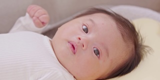 一个快乐的新生儿躺在婴儿床上，对着镜头微笑。可爱的亚洲新生儿，天真的眼睛舒适和放松。新生儿摄影概念