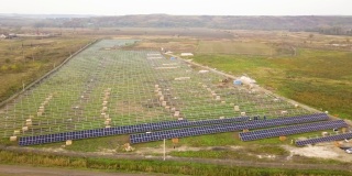 在绿地上建造太阳能发电厂的鸟瞰图。生产清洁生态能源的电板装配