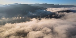 鸟瞰图，在日出时，云雾快速移动，覆盖着群山