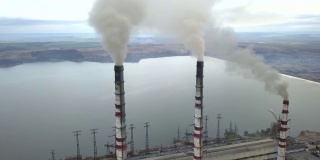 从空中俯瞰高耸的烟囱管和灰色的烟从燃煤电厂。用化石燃料发电。