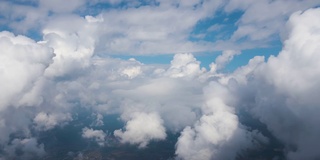 从飞机窗口俯瞰，高空的地面上覆盖着白色蓬松的积云