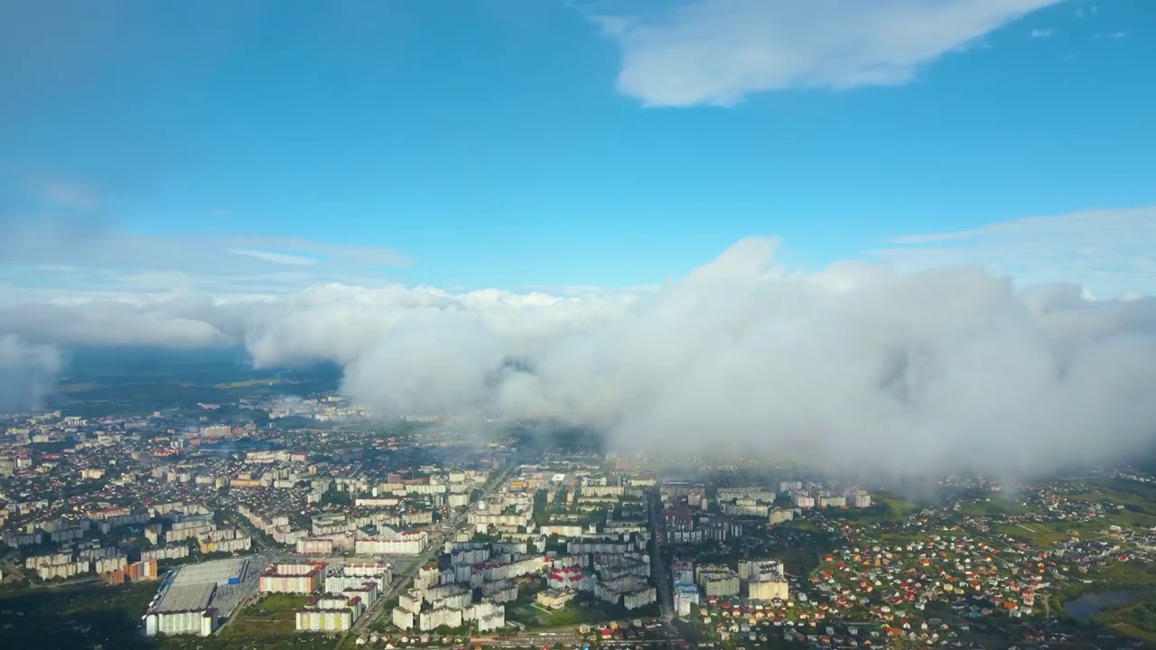 高空鸟瞰图，远处的城市被暴雨前形成的蓬松的积云所覆盖