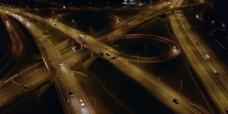 无人机在夜间拍摄的高速公路上，桥梁和高架桥穿过十字路口。汽车运输的运动。波兰华沙郊区。