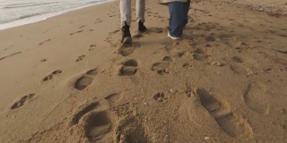 在多云的日出或日落时，幸福的情侣漫步在野生的海滩上