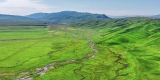 空中拍摄的新疆那拉提草原上的绿色草地、河流和山地景观。