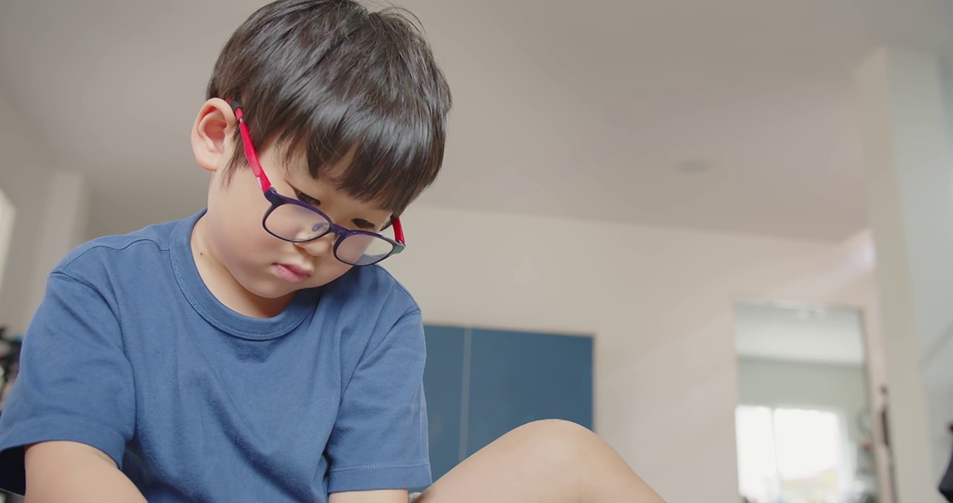 肖像可爱的亚洲学龄前儿童小男孩与眼镜玩玩具在客厅在家里