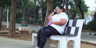 超重的女人在公园慢跑喝酒