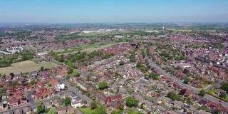 从空中拍摄的西约克郡韦克菲尔德奥塞特村中心的镜头，可以看到一个阳光明媚的夏天，从上方俯瞰英国的住宅、道路和街道