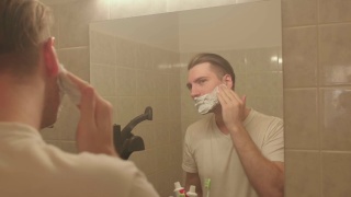 男士将剃须泡沫涂在脸上。他在算盘上搓手，准备刮脸。视频素材模板下载