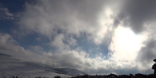 冬天的风景。蓝色的天空上飘动着毛茸茸的白云。山上覆盖着雪
