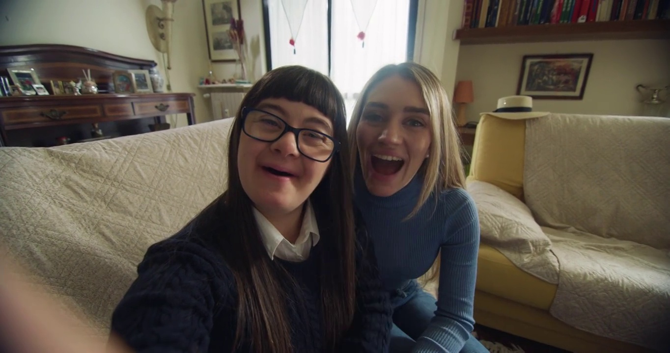 快乐的姐姐和十几岁的女孩的电影镜头与下来，使技术视频一起打电话给朋友或家人在家里。交谈的概念，残障，残障，媒体，爱情，友谊
