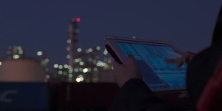 女主管使用具有未来现实技术的数码平板电脑在夜间检查石化工厂