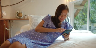 亚洲女性在家用智能手机在卧室网购。